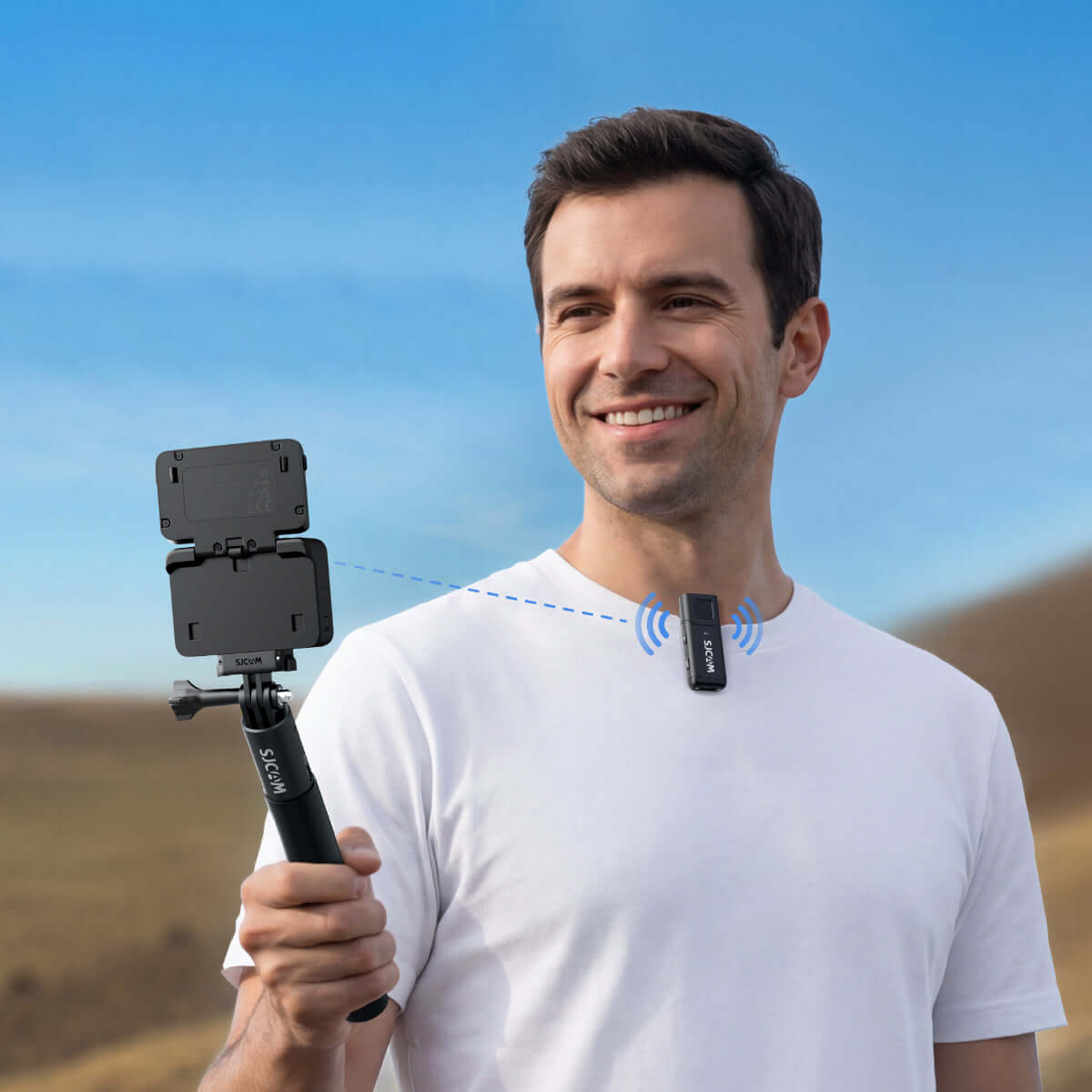 Man using M4 Wireless Microphone with smartphone on a selfie stick in an outdoor setting.