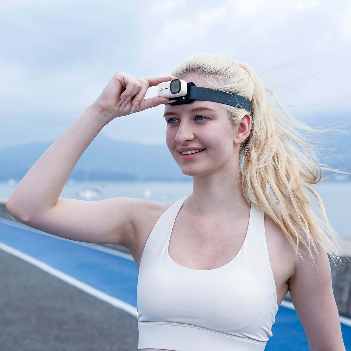 Woman outdoors wearing a Magnetic Head Strap while adjusting its position.